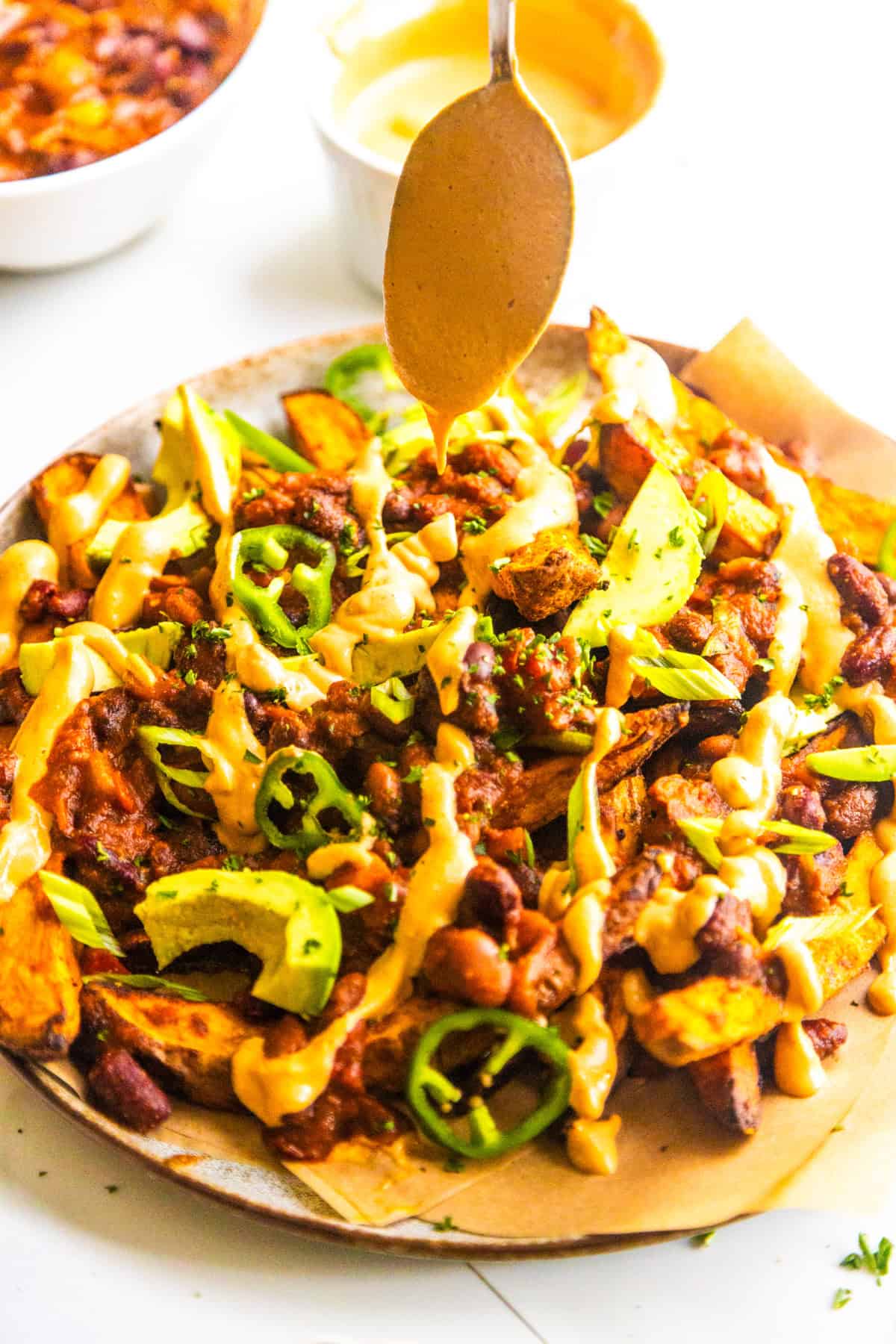 Chipotle sauce drizzling over loaded chili sweet potato fries.