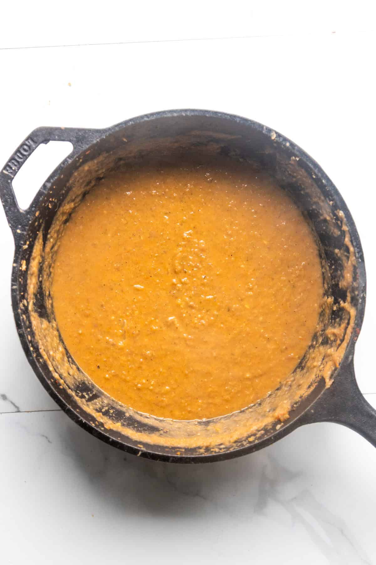 Refried bean filling for vegan taquitos in a cast iron pan.