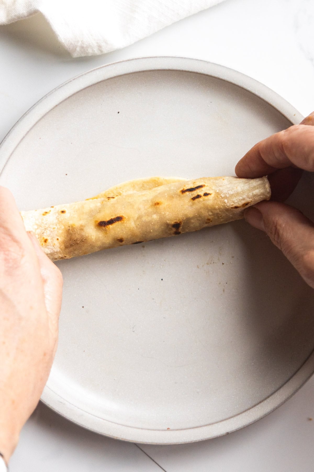 Vegan taquito being rolled on a plate.