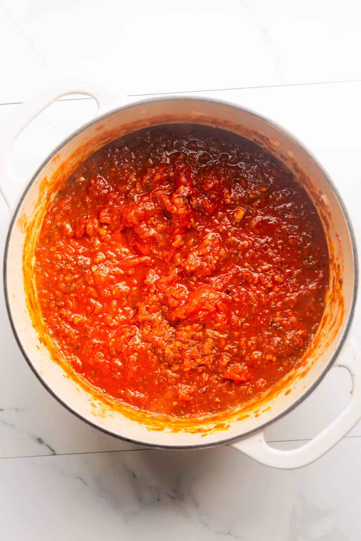 San Marzano tomatoes and seasonings added to a dutch oven with sautéed veggies.