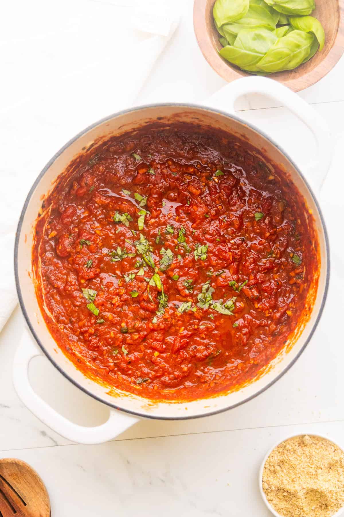Hearty marinara sauce in a dutch oven topped with fresh basil.
