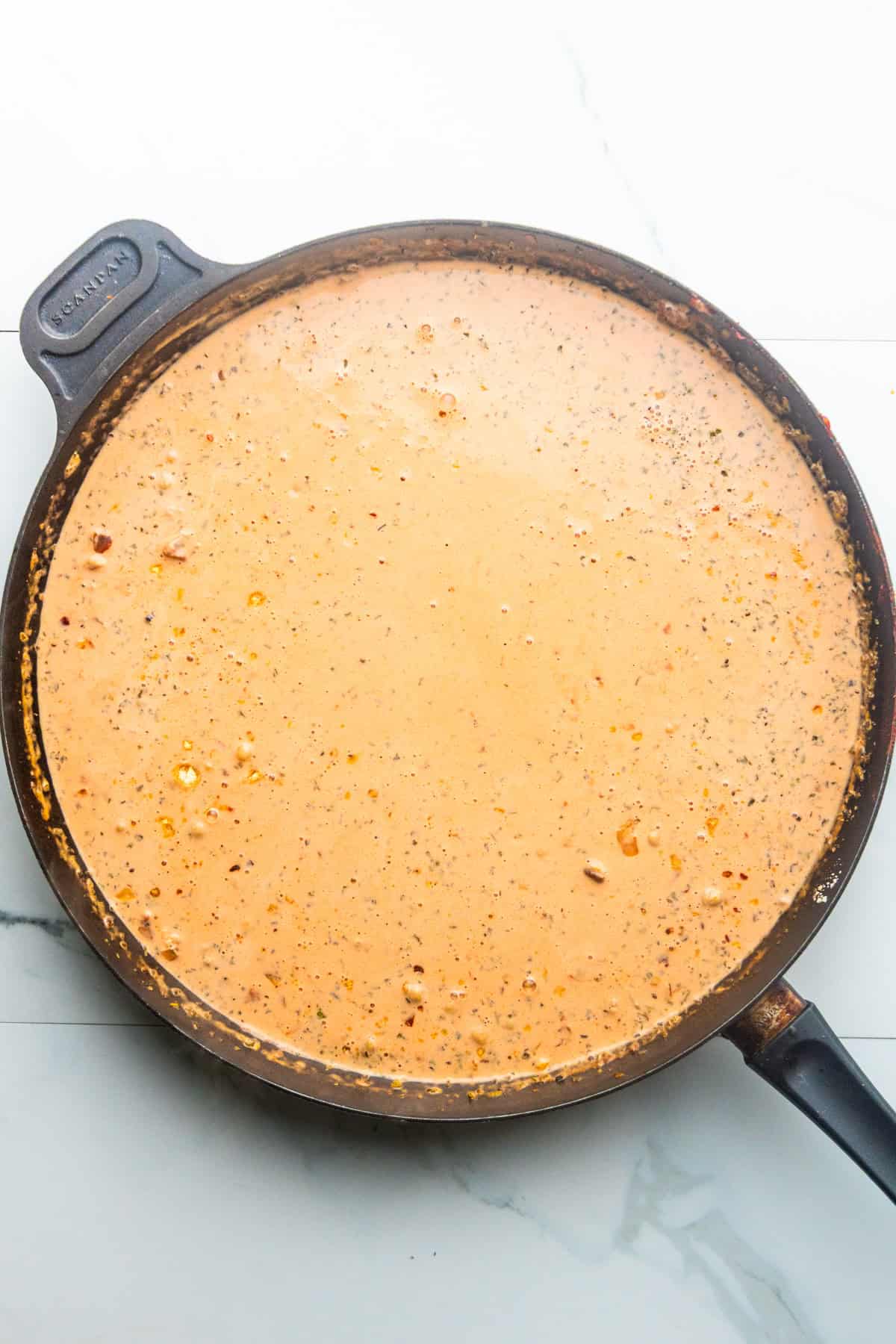 Coconut milk added to a skillet with sautéed veggies and tomato paste.