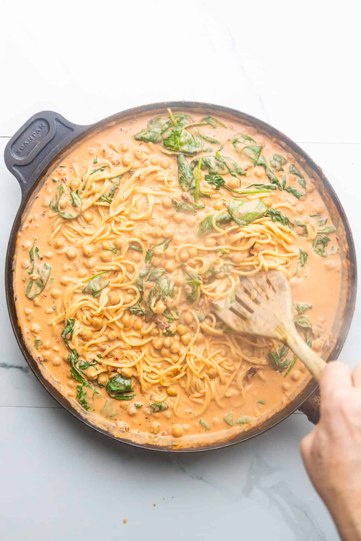 Marry me chickpeas with pasta being stirred in a skillet.