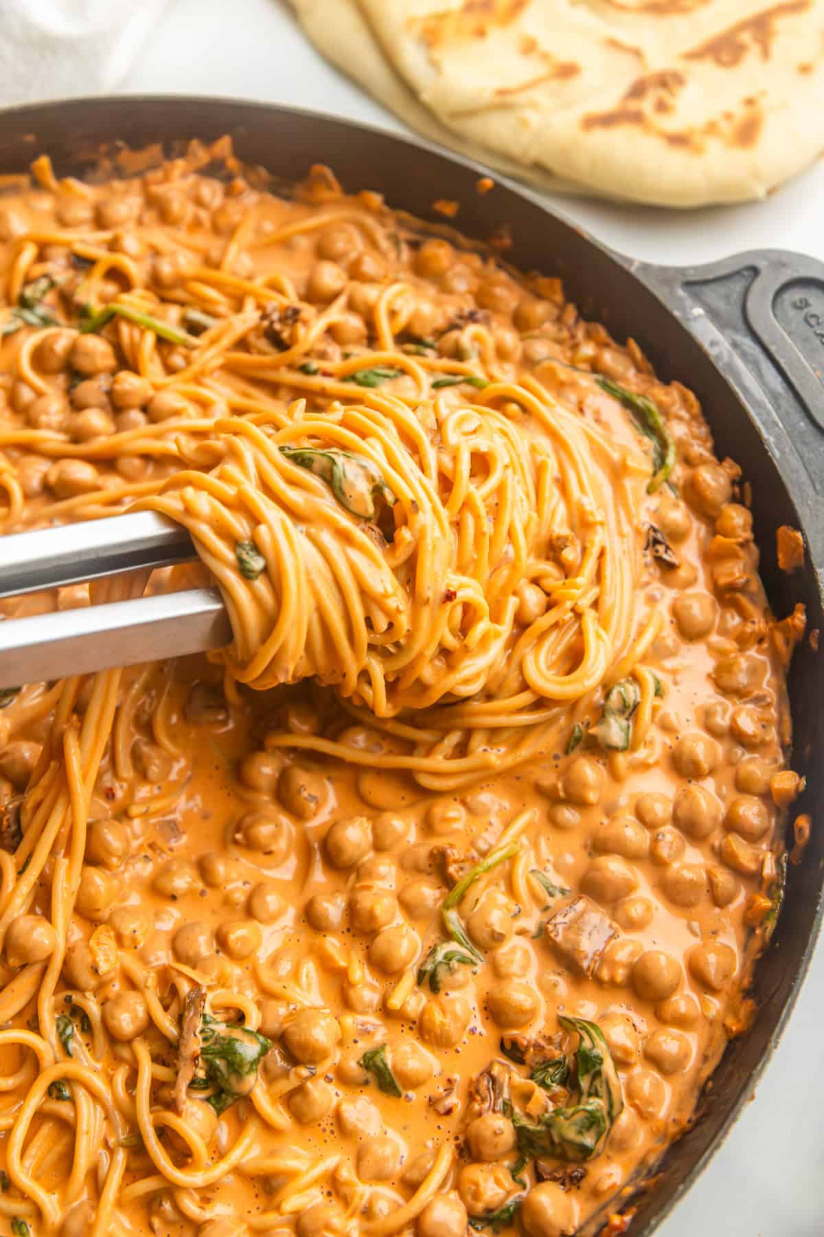 Marry me chickpeas with pasta in a skillet with naan on side.