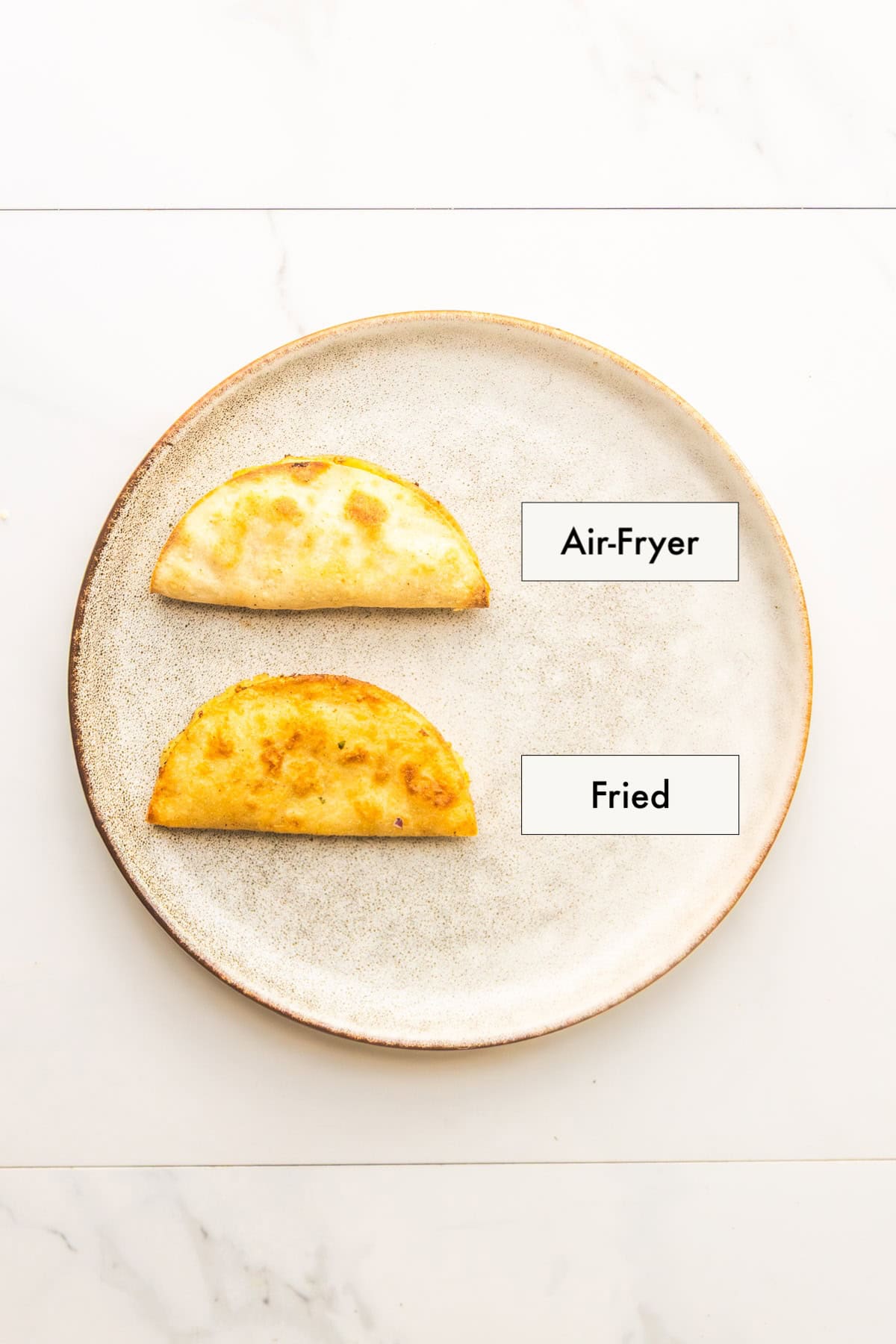 Two different potato tacos from different cooking methods arranged on a plate.