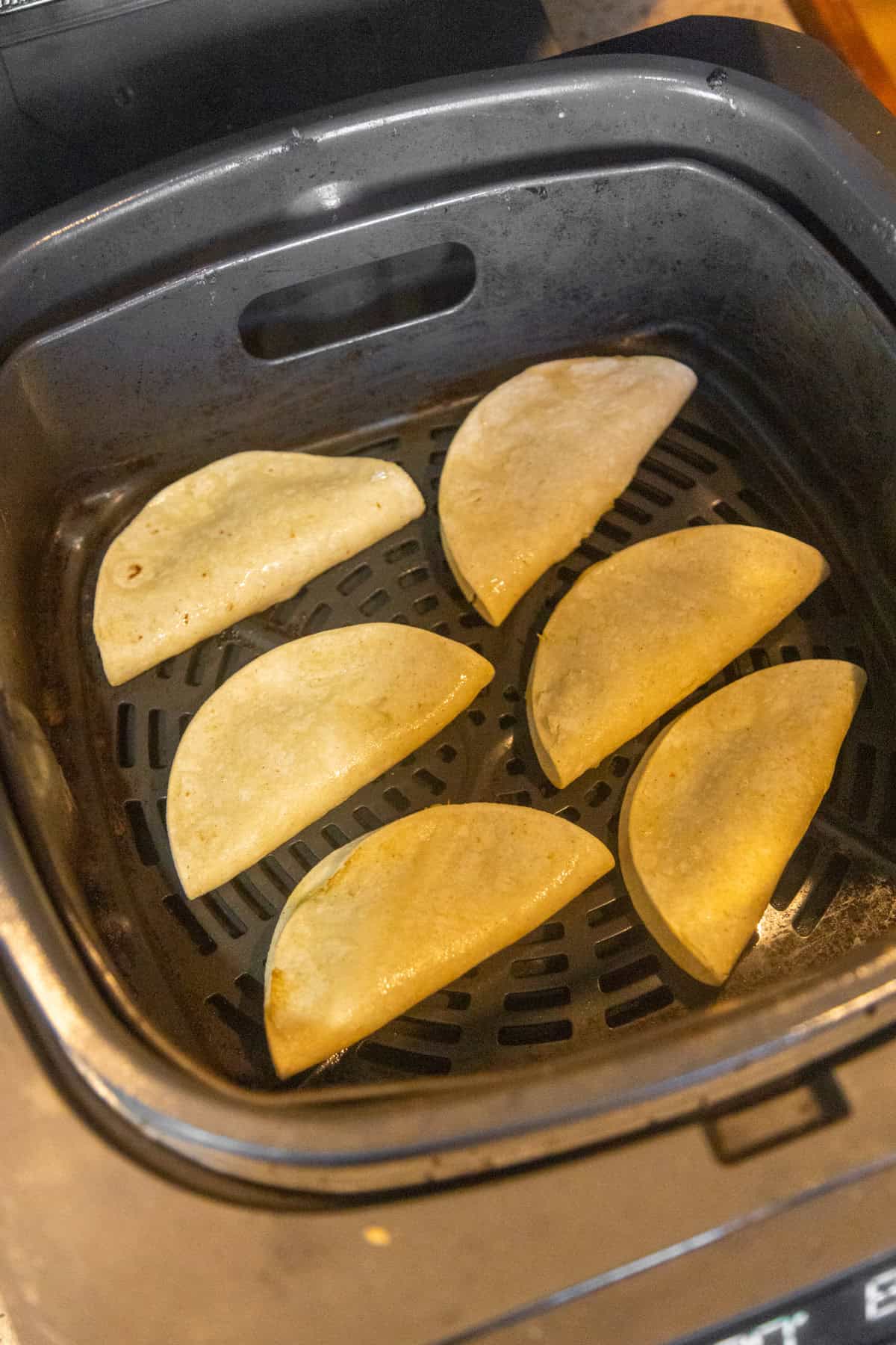 Crispy potato tacos cooking in an air fryer.
