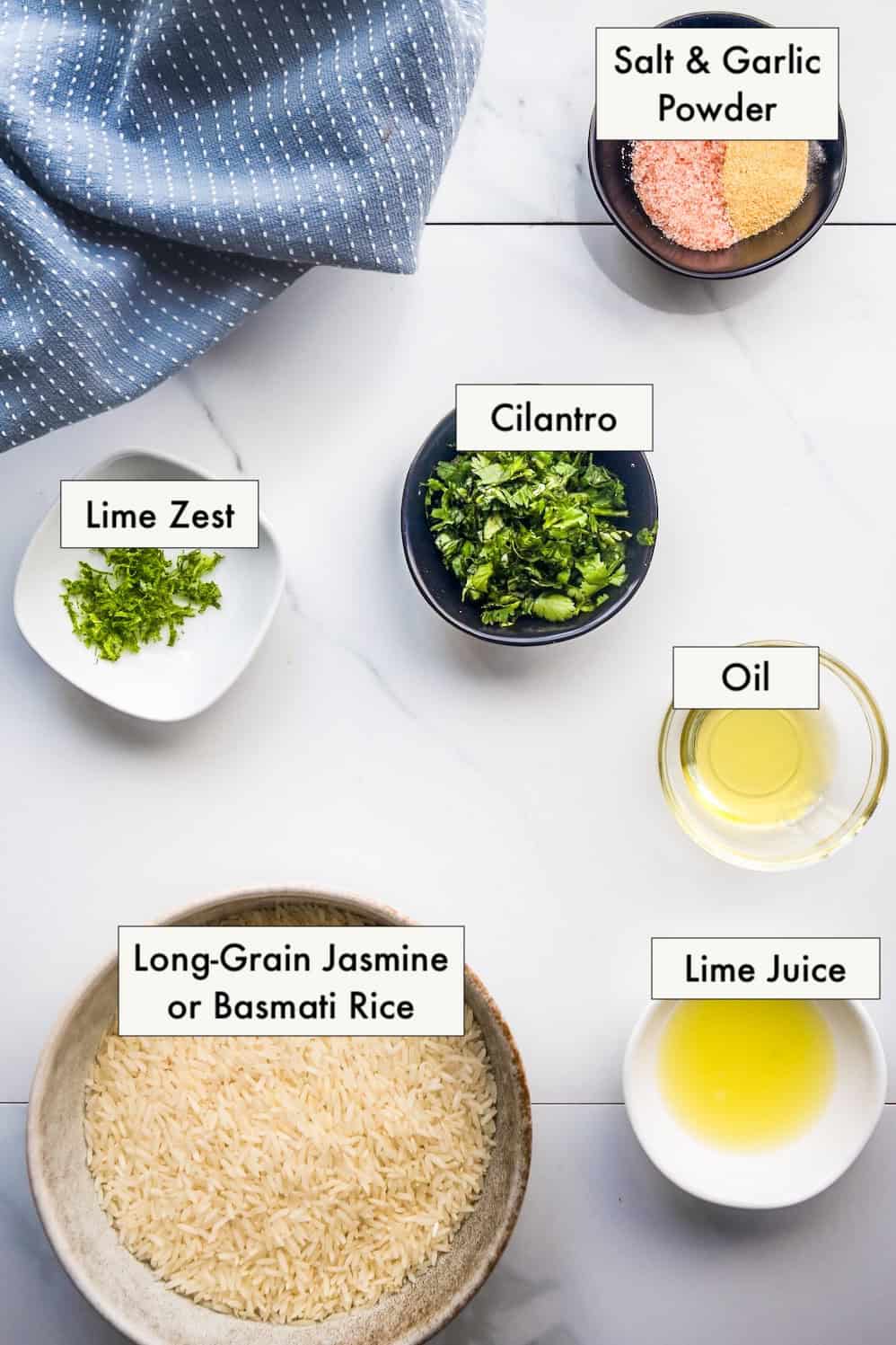All ingredients to make rice for burritos (cilantro lime rice) in labeled bowls on a counter.