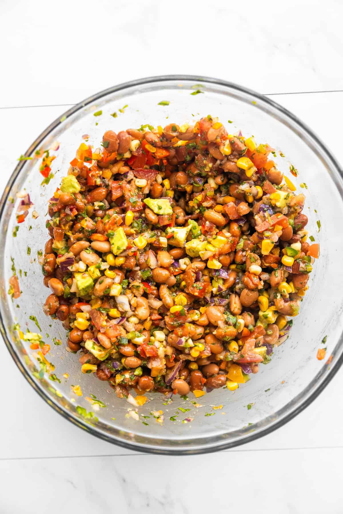 Pinto bean corn salad in a mixing bowl with avocado mixed in.