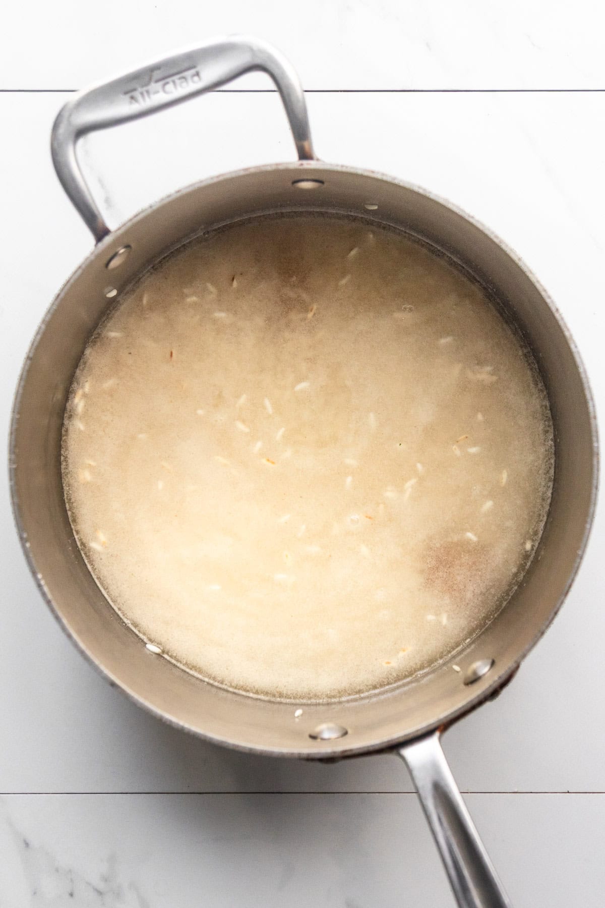 Sautéed rice, seasonings, and water in a pot.
