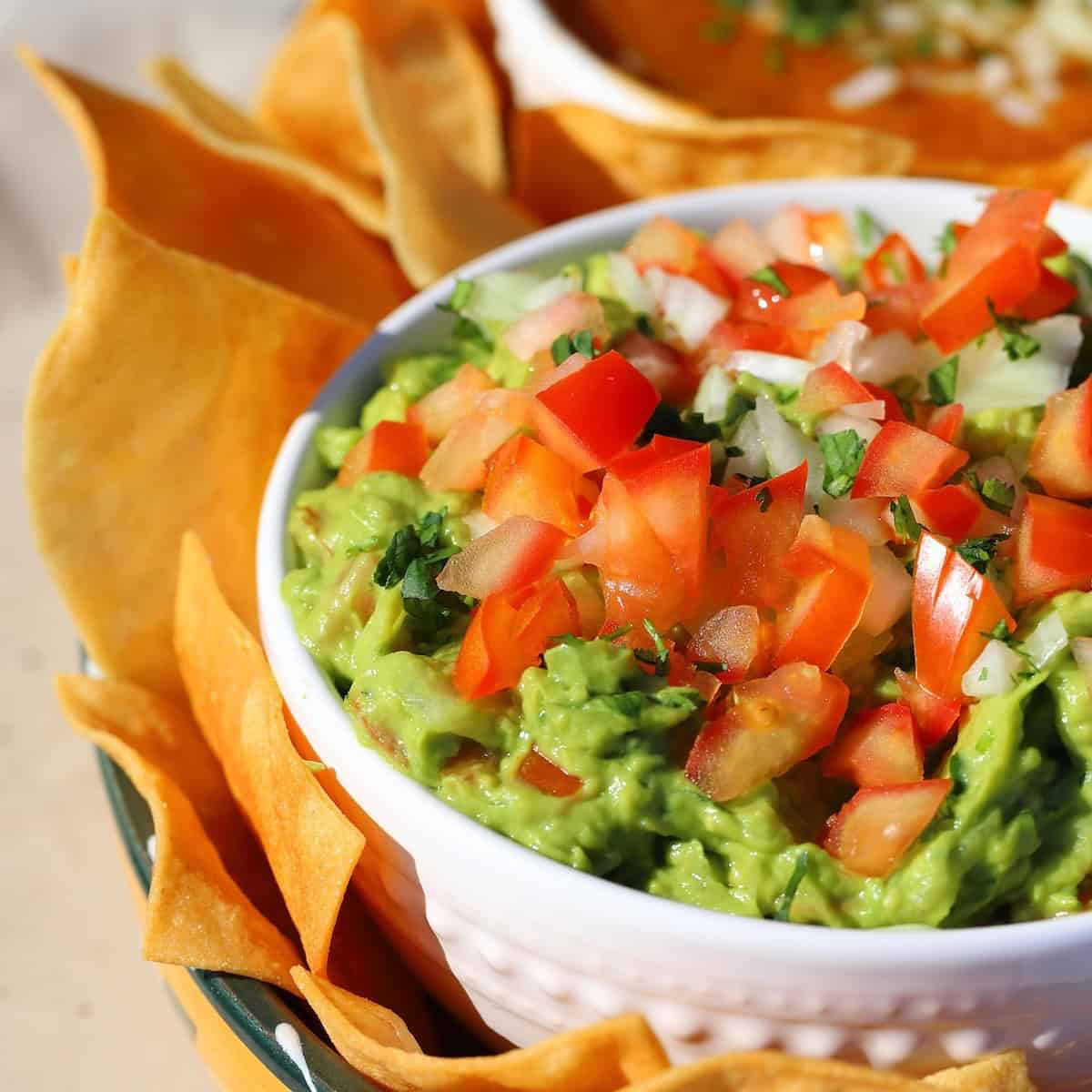 Fresh homemade guacamole in a bowl with chips on the side.