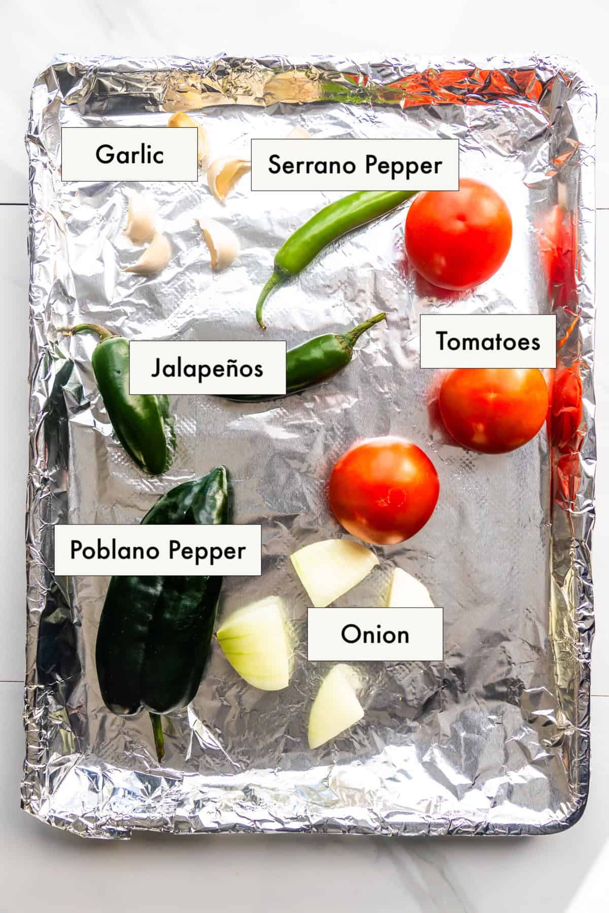 All ingredients for molcajete salsa recipe on a baking sheet.