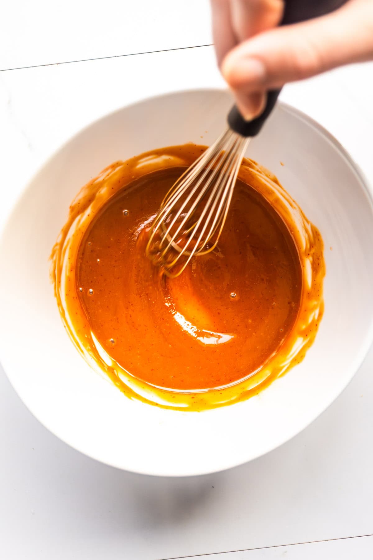 Glaze for sweet and spicy maple sriracha tofu mixing in a bowl.