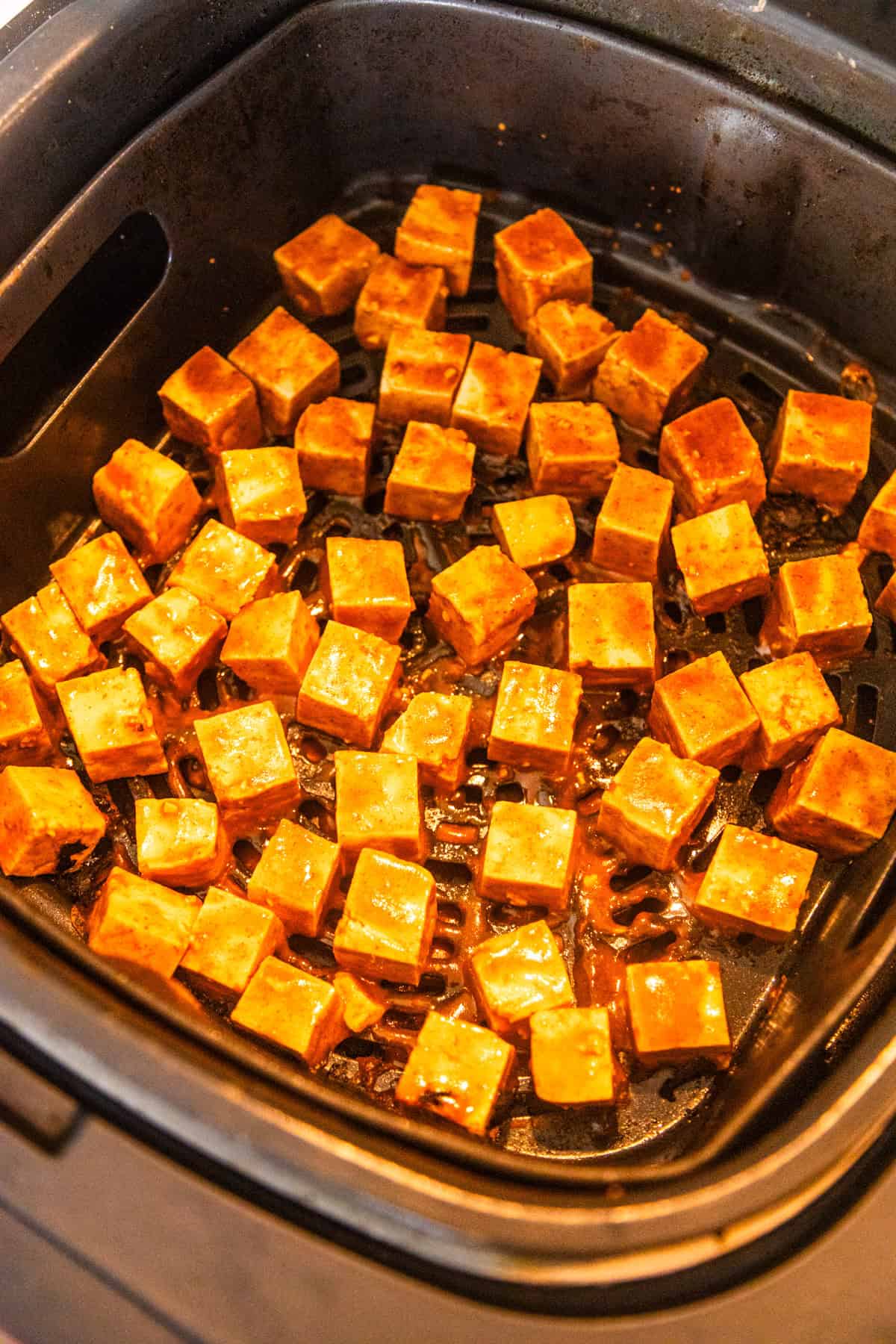 Sweet and spicy maple sriracha tofu placed in an air fryer.
