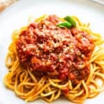 Veg loaded vegan spaghetti sauce served on pasta and topped with fresh basil.