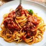 Fork twirling vegan spaghetti sauce served with noodles on a plate.