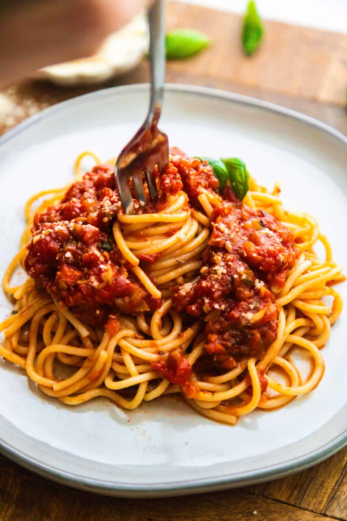 Fork twirling vegan spaghetti sauce served with noodles on a plate.