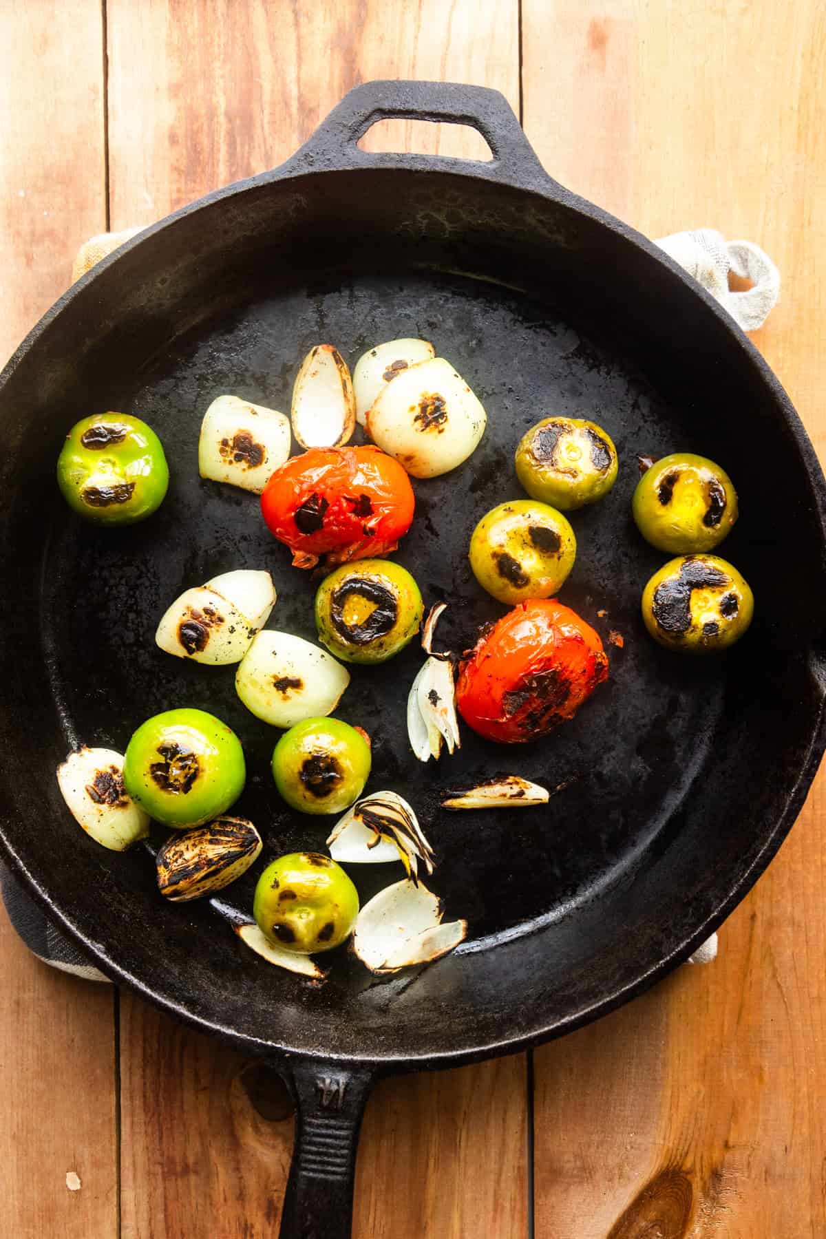Veggies charring in a cast iron pan.
