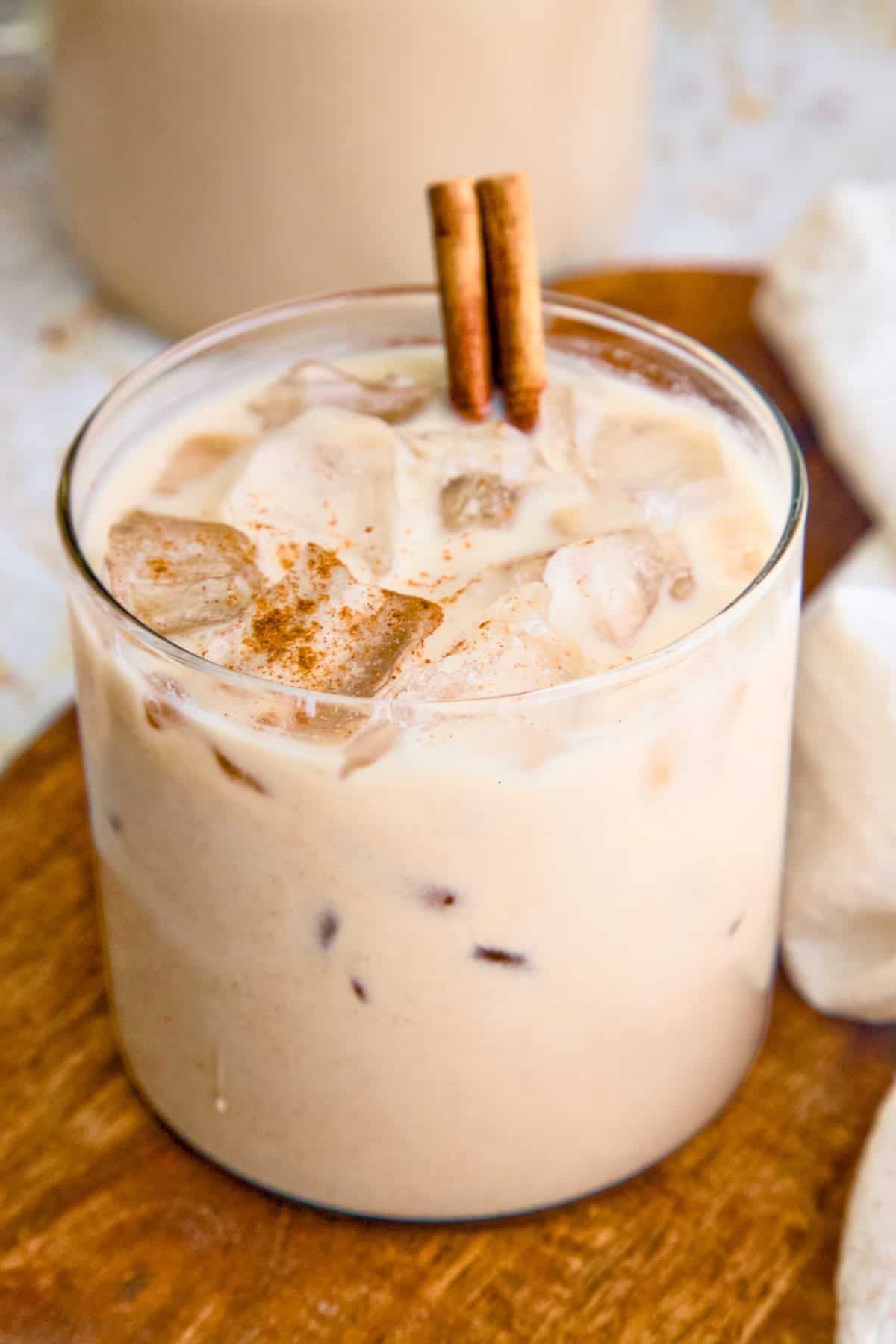 Vegan horchata (Mexican rice milk) in a large glass with ice and topped with a cinnamon stick.