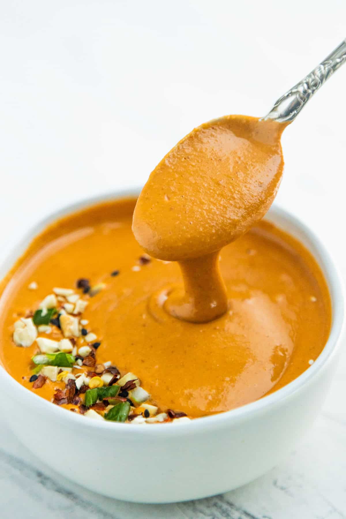 Asian peanut sauce in a bowl with a spoon in it.