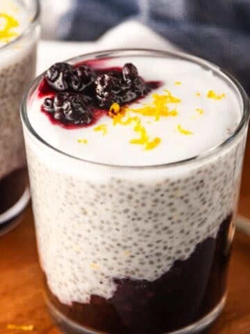 Lemon blueberry chia pudding in a glass topped with vegan yogurt and lemon zest.