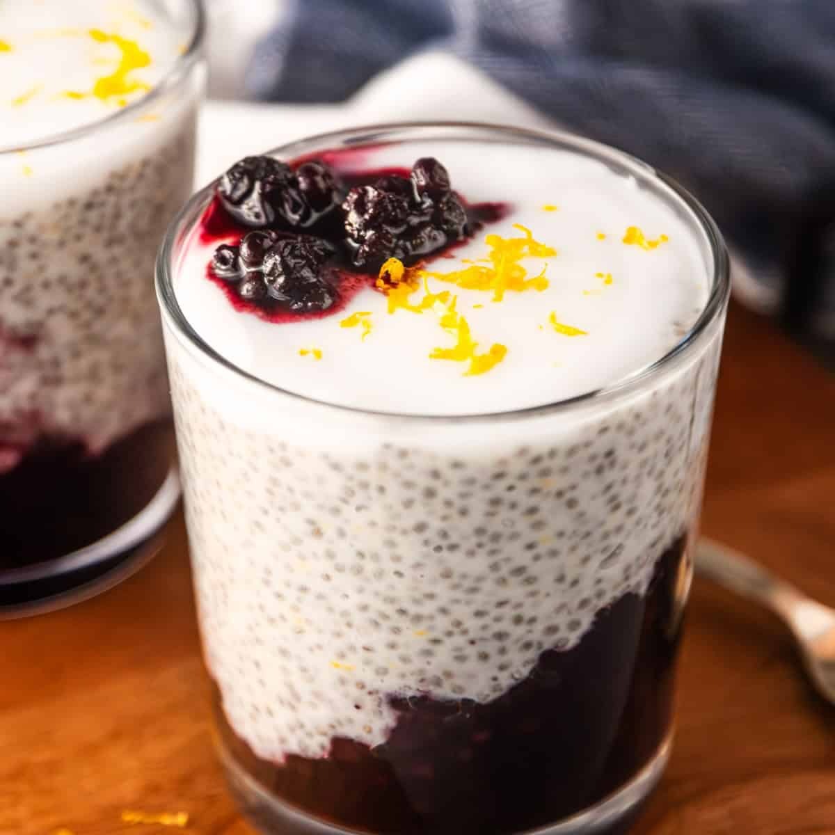 Lemon blueberry chia pudding in a glass topped with vegan yogurt and lemon zest.