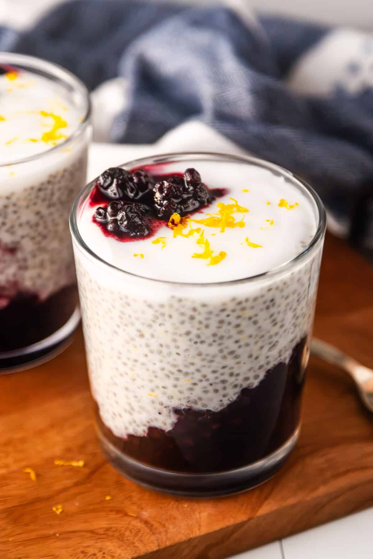 Lemon blueberry chia pudding in a glass topped with vegan yogurt and lemon zest.