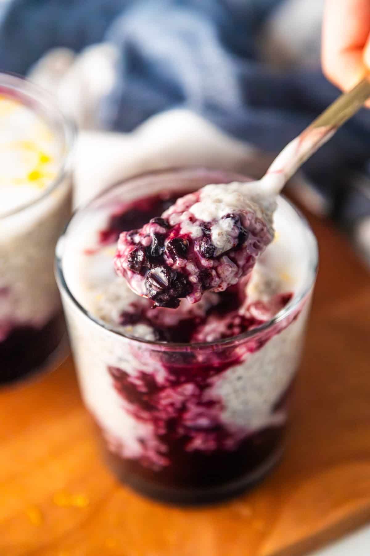 Spoon holding up lemon blueberry chia pudding.