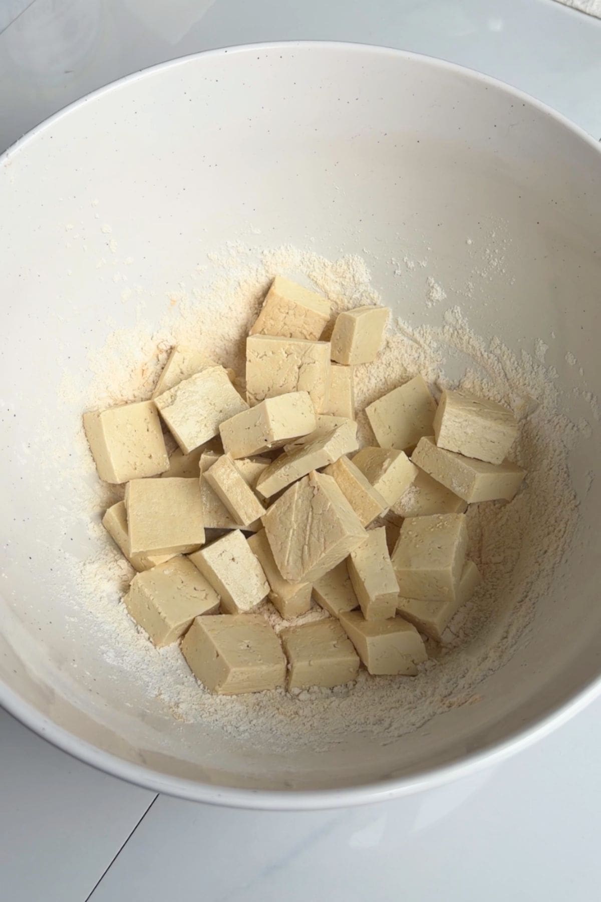 Tofu in a bowl mixing with spices.