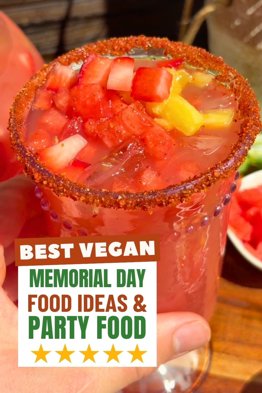 Aguas frescas in a glass with a Tajin rim and topped with chopped watermelon and pineapple.