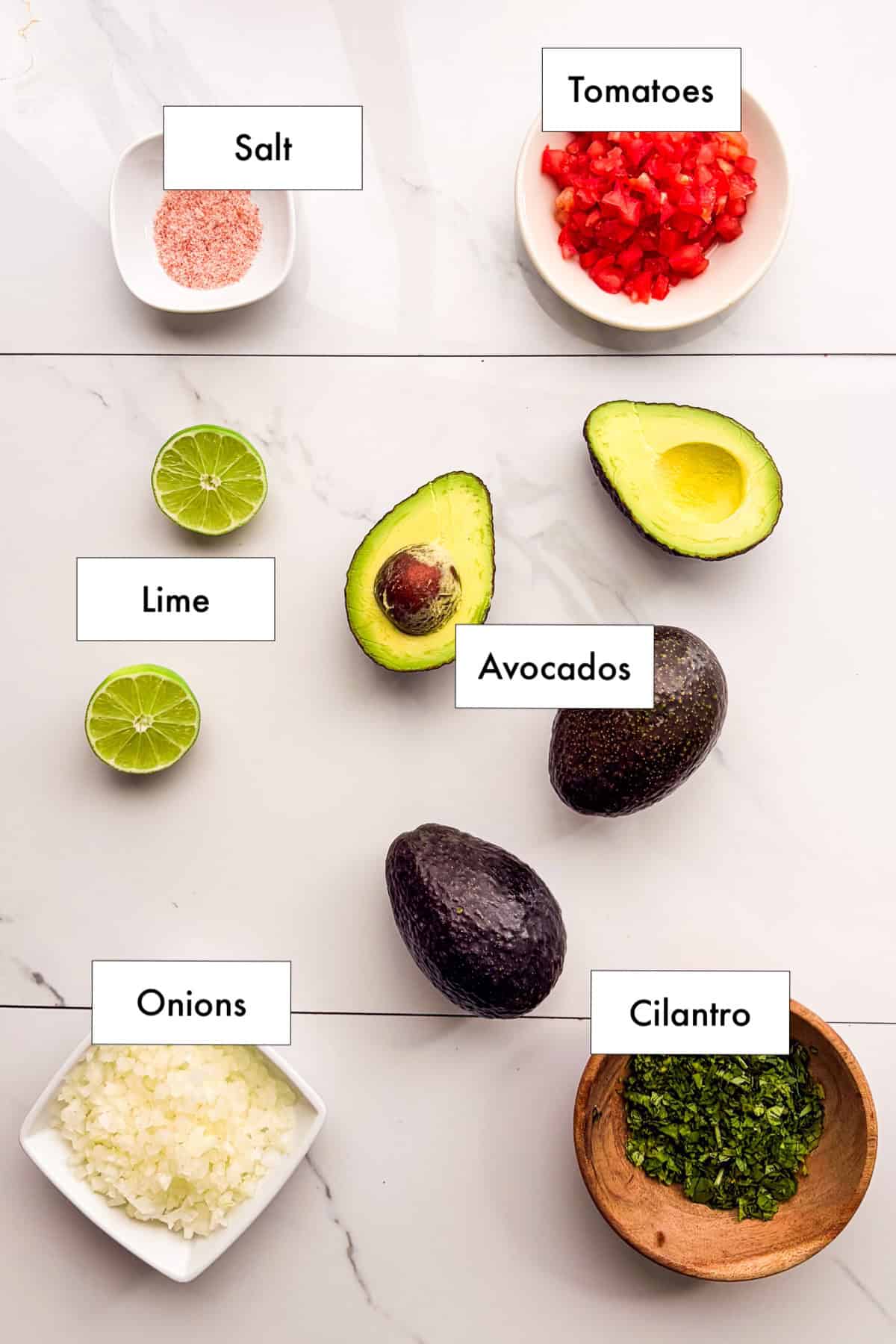 All ingredients needed to make fresh guacamole laid out on a counter.