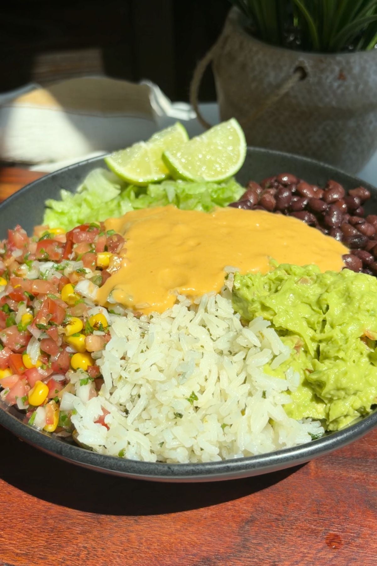 Rice, beans, lettuce, pico de gallo, guacamole, and salsa in a bowl.