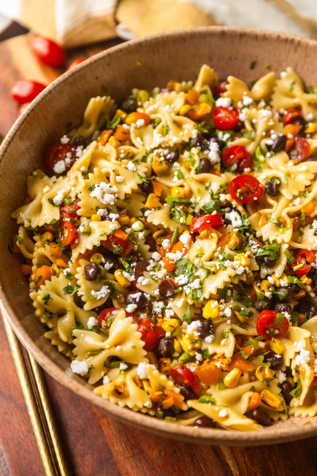Southwest pasta salad in a bowl on a counter with salad spoons on the side.