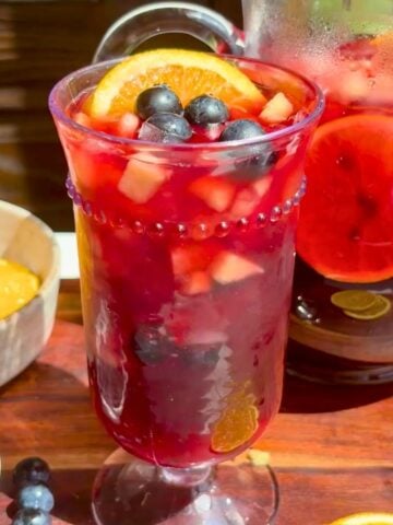 Pineapple hibiscus sun tea in a glass topped with fresh fruit.