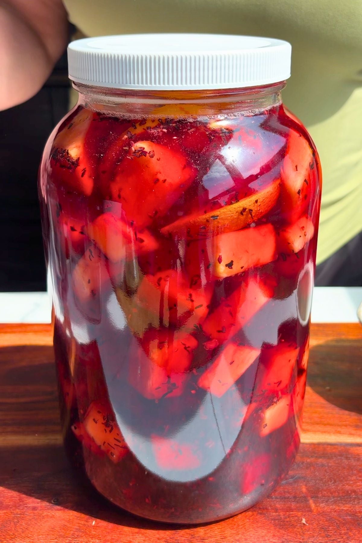 Pineapple hibiscus sun tea in a large galloon jar steeping in the sun.