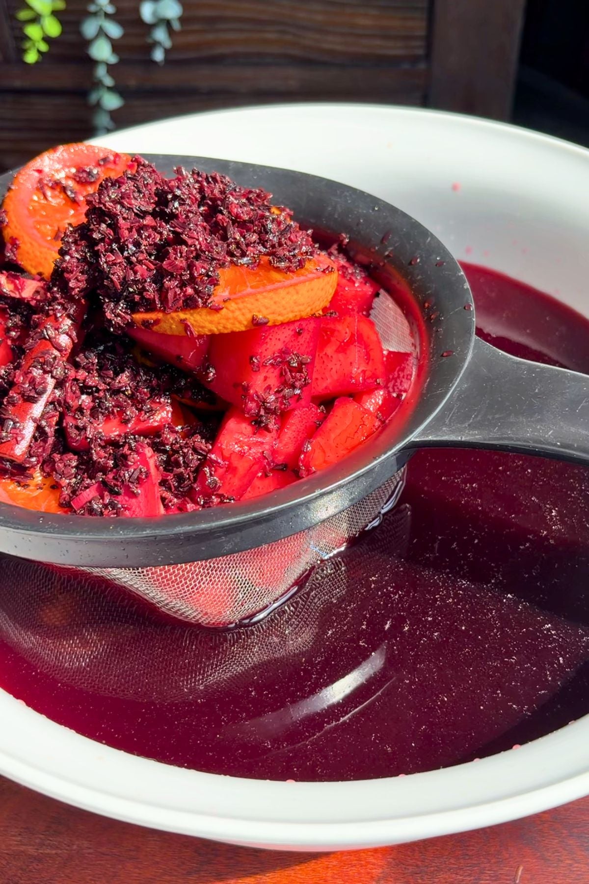 Pineapple hibiscus sun tea straining into a large bowl.