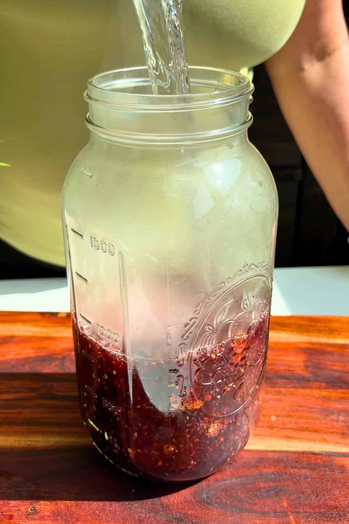 Pineapple hibiscus sun tea steeping in a large glass with hot water.