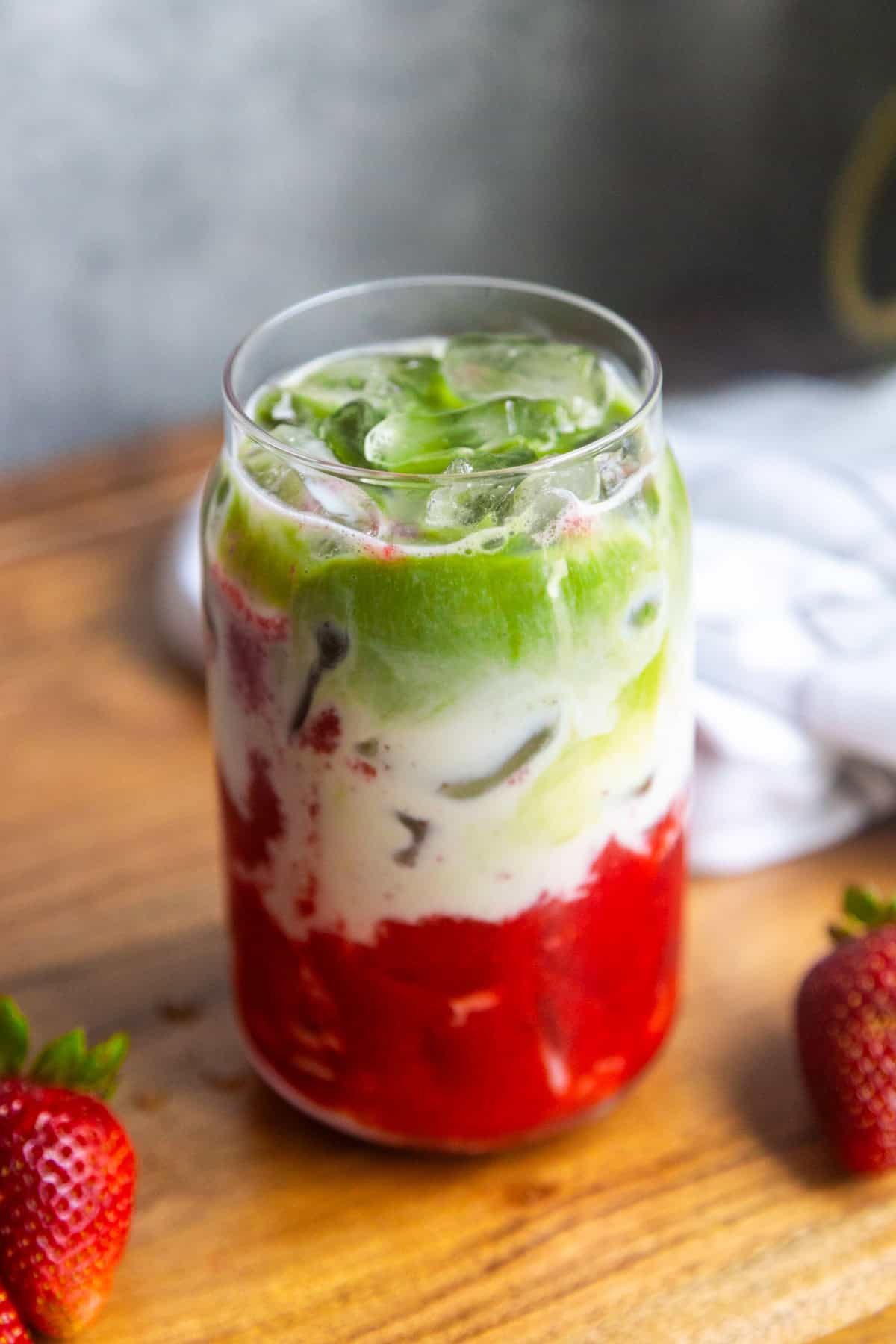 Strawberry matcha latte in a glass on a counter.