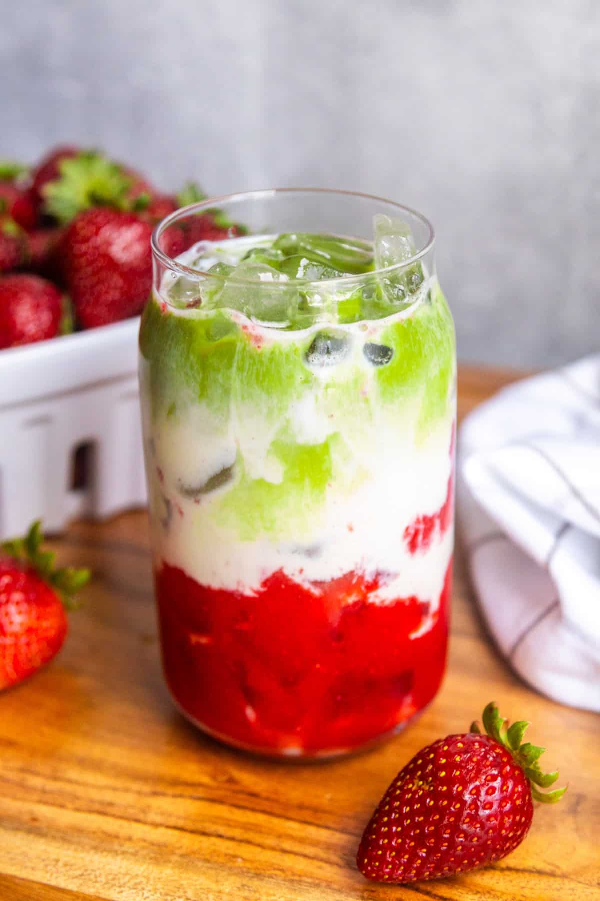 Strawberry matcha latte in a glass with fresh strawberries on the side.