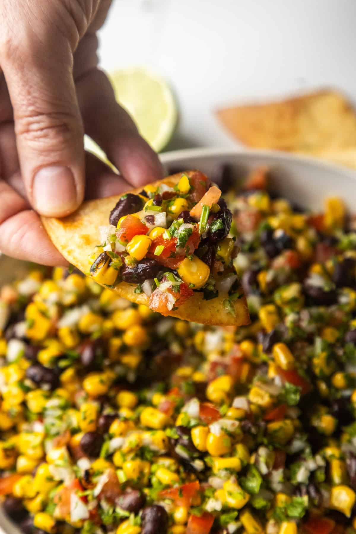 Chip dipping into a bowl with black bean and corn salsa dip.