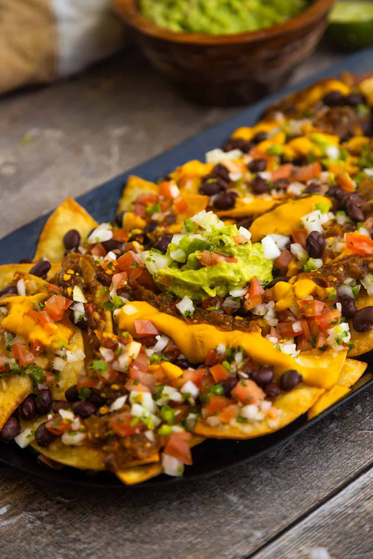 Vegan loaded nachos served on a comal topped with guacamole.